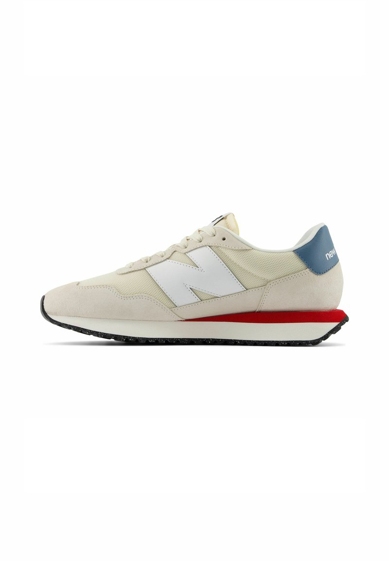 Beige Sneaker mit weißen Akzenten und einer blauen Ferse. Verfügt über ein texturiertes Obermaterial, einen roten Mittelsohlenstreifen und eine schwarze Gummisohle.