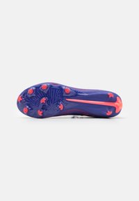 Suela de tachones de fútbol morada con pinchos rosas; presenta una superficie texturizada y una forma aerodinámica, diseñada para ofrecer tracción en superficies de hierba.