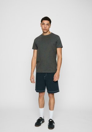 Sötét szürke pamut póló sötét farmer rövidnadrággal, fehér varrással, fehér bokazoknival és fekete edzőcipővel párosítva.