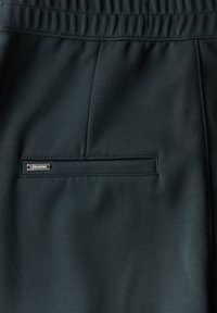 Mörkgröna, stretchiga byxor i tyg med flat front, elastisk midja och en liten, sydd ficka med en metalllogotyp.