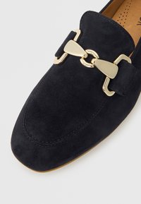 Navy blue suede loafer featuring a gold-tone hardware accent and a rounded toe design with stitching details.