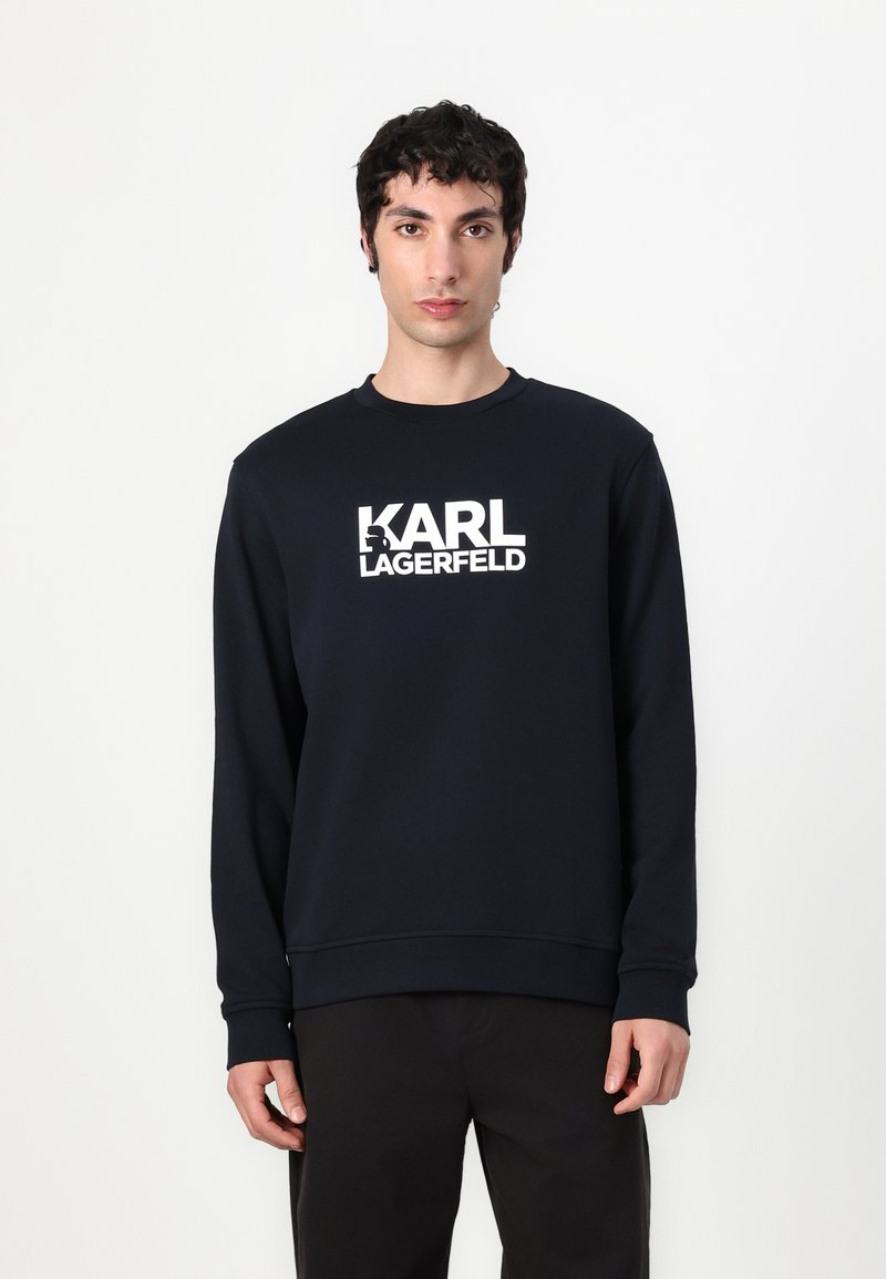 Navy dukserica s bijelim logotipom "KARL LAGERFELD". Izrađena od pamuka, s okruglim izrezom, dugim rukavima i rebrastim manžetama i donjim rubom.