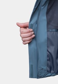 Jasnoniebieska kurtka z siateczkowym podszewką, zapinana na zamek, z akcentami na rzepy. Posiada sznurówkę w dolnej części i gładką teksturę materiału.