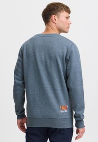 Grå bomulds sweatshirt med rund halsudskæring, ribbede ærmer og kant. Har orange logo tekst på ryggen, hvilket viser et afslappet design.