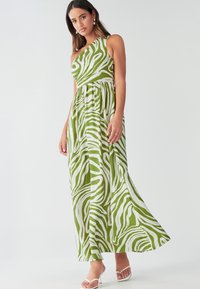 Grøn og hvid maxikjole med et skulderdesign, der har en flydende silhuet og zebrastribet mønster i letvægtsstof.