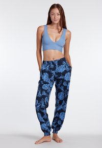 Svetlomodrá crop top s výstrihom do V v kombinácii s námorníckymi nohavicami s modrým listovým vzorom, elastickými manžetami a bočnými vreckami.
