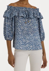 Modrá květinová top s odhalenými rameny, ruffled výstřihem a nafouknutými rukávy. Vyrobeno z lehkého materiálu, má přiléhavé tělo a stahovací detaily.