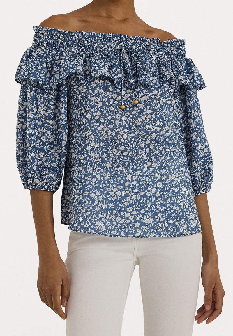 Modrá květinová top s odhalenými rameny, ruffled výstřihem a nafouknutými rukávy. Vyrobeno z lehkého materiálu, má přiléhavé tělo a stahovací detaily.