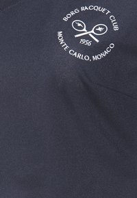 Námořnická látka s tištěným bílým logem "BORG RACQUET CLUB" s překříženými raketami a textem "MONTE CARLO, MONAKO" a "1956".