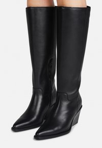 Bottes noires en cuir montantes jusqu'au genou, présentant un bout pointu, un talon en coin et une fermeture éclair sur le côté. Texture lisse avec un design élégant.