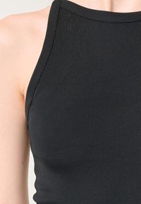 Schwarzes, geripptes Tanktop mit hohem Kragen und schmalen Trägern, das eine figurbetonte Silhouette und eine glatte Textur betont.