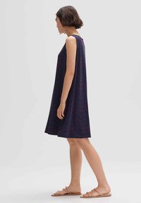 Marineblaues ärmelloses Kleid mit lockerer Passform, das ein strukturiertes Muster in Rosa und Rot aufweist und knapp über dem Knie endet. Wird mit flachen Sandalen getragen.