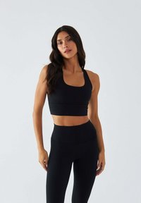Czarny sportowy top z krótkim krojem, z dekoltem w kształcie litery U i szerokimi ramiączkami, zestawiony z czarnymi legginsami z wysokim stanem, gładka tekstura, dopasowany krój.