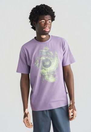 T-shirt viola in cotone con collo rotondo e maniche corte. Presenta una grafica verde e nera al centro davanti con la scritta "New Balance Athletic".