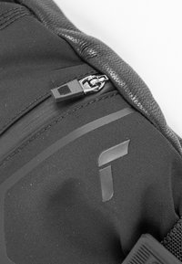 Nahaufnahme eines schwarzen Rucksacks mit strukturiertem Stoff, Reißverschlussdetails und einem Logoakzent. Glatte Außenseite mit verstärkten Kanten.