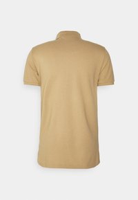 Béžov�á polo triko, krátké rukávy, klasický límec, hladká textura, jednoduchý design, žádné viditelné vzory nebo akcenty, pohled zezadu.