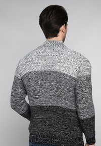 Gestrickter Pullover in einem Farbverlauf von Grau zu Schwarz. Besitzt einen strukturierten Stoff mit hohem Kragen sowie gerippten Bündchen und Saum.