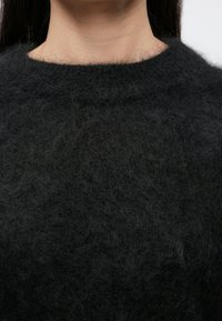 Tumehall kampsun, pehme ja kohev tekstuur ning ümara kaelusega. Kangas paistab kerge ja veidi veniv.