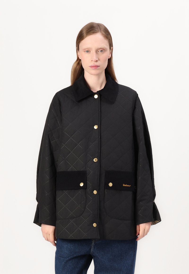 Quilted black jacket, featuring a flat collar, gold hardware, two front pockets, and subtle stitching pattern. Made of textured material.