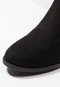 Black suede ankle boot with a rounded toe, a smooth texture, and a black rubber sole. The upper has no visible patterns or hardware.