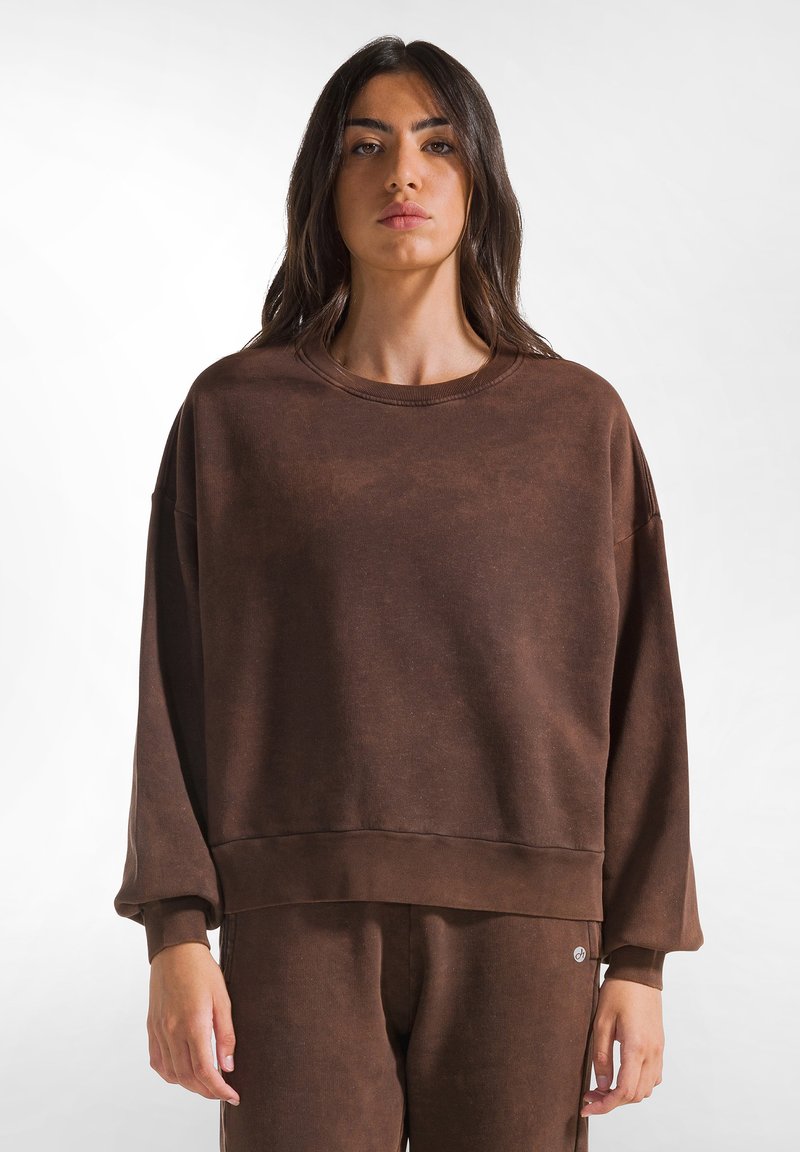 Felpa oversize marrone realizzata in un tessuto morbido con un aspetto texture, caratterizzata da un collo rotondo e una vestibilità rilassata.