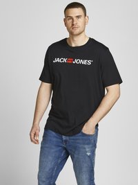 Musta puuvillainen T-paita, jossa on valkoinen logo printti "JACK & JONES" rinnassa. Yhdistetty kuluneisiin siniseen farkkuun.