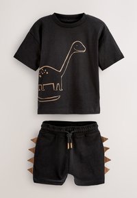 Tenue noire pour tout-petit avec un motif de dinosaure au long cou sur le t-shirt et des pics de dinosaure en tissu le long des côtés du short.