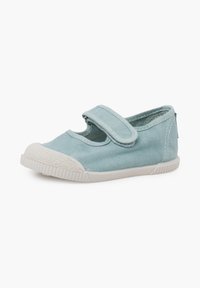 Chaussure pour enfant en toile bleu clair avec embout en caoutchouc blanc, semelle, et bride ajustable à fermeture auto-agrippante sur fond uni.