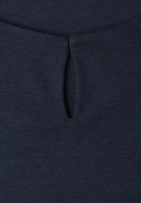 Close-up of dark blue fabric showing a vertical keyhole slit detail at the center, likely part of a garment neckline.