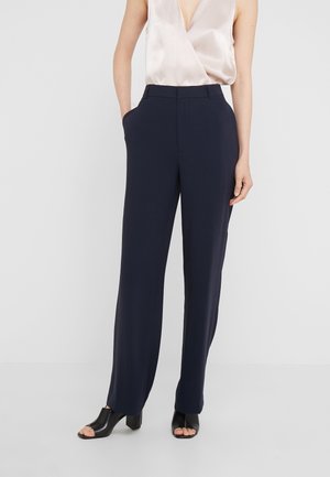 Pantalon large marine avec poches, en tissu lisse. Associé à un haut en satin léger et des talons ouverts noirs.
