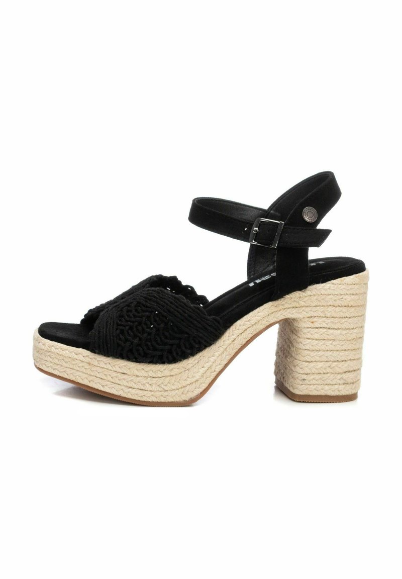 Sandalia de tela negra con plataforma de cuerda trenzada y tacón de bloque. Presenta una tira ancha y una correa en el tobillo con una hebilla ajustable.