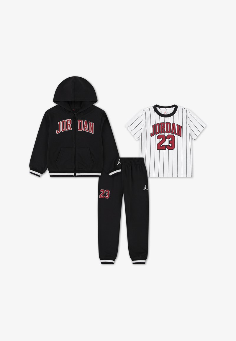 Melna kapuce ar rāvējslēdzēju un "JORDAN" logo, balta T-kreklu ar svītrām un "JORDAN 23," un melnas sporta bikses ar logo un numuru 23.