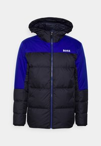 Černá a modrá vycpaná bunda se zipovým zapínáním a kapucí. Má jednolitou modrou horní část a logo „BOSS“ na hrudi.