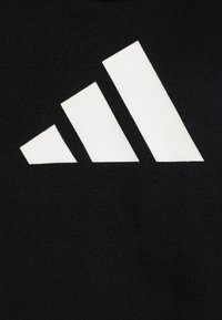 Tissu noir avec un grand graphique blanc représentant trois bandes diagonales de tailles variées, créant un effet visuel dynamique.