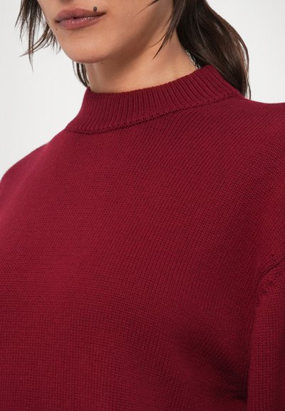 Camisola de malha cor de vinho com gola alta canelada, apresentando textura suave e detalhes subtis de pontos.