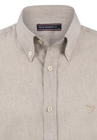Lys beige linned skjorte med knapkrave. Den har en subtil tekstur og et broderet fuglelogo på venstre bryst.