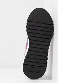 Semelle d'une basket avec de profondes rainures horizontales et le nom de la marque "Bull Boxer" embossé sur le talon en caoutchouc noir.