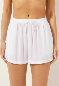 Pantalones cortos ligeros y blancos con cinturilla elástica y cordón ajustable. Cuenta con una textura suave y dobladillo enrollado.