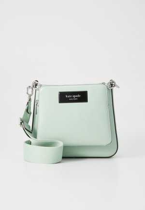Sac bandoulière vert clair avec sangle large réglable, ferrures argentées et poche avant zippée étiquetée « kate spade new york ».