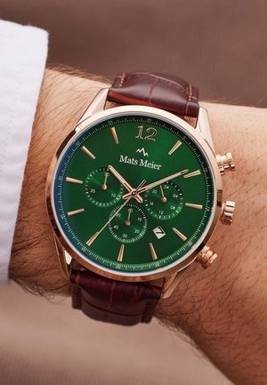 Chronograafhorloge met een groene wijzerplaat, kast in roségoudkleur, leren band in bruin, grote uurmarkers en drie sub-dials.