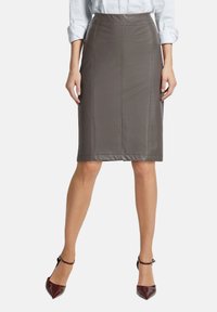 Grijze leren kokerrok met verticale naden en een aansluitende pasvorm, gestyled met spitse bordeauxrode hakken.