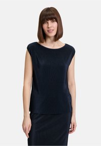 Marineblauw ribbeltop met een ronde halslijn en korte mouwen, met een losse pasvorm en zachte textuur, onderdeel van een bijpassende tweedelige set.