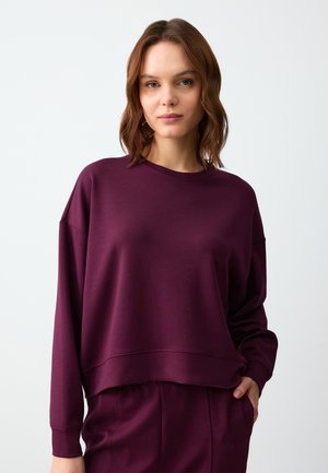 Felpa corta bordeaux con maniche lunghe, scollatura rotonda e polsini a costine. Tessuto morbido e strutturato con vestibilità comoda.