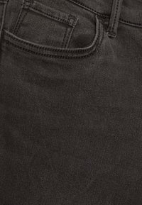 Tejido de mezclilla negra con un bolsillo frontal, textura suave y detalles de costura simples, adecuado para el uso casual.