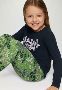 Marineblauw shirt met lange mouwen en witte tekst "TALENT 2024", gecombineerd met groene leggings met bloemenpatroon en roze en blauwe bloemen.