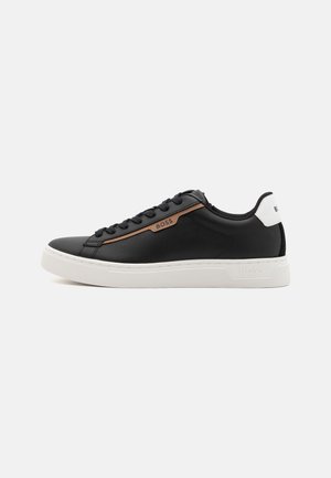 Sneaker in pelle nera con suola in gomma bianca, striscia di accento marrone e lacci tonali. Presenta un logo stampato in rilievo sul tallone e sul lato.