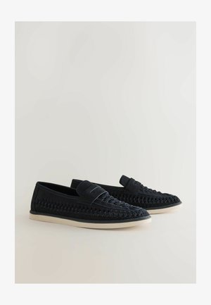 Dunkelblaue gewebte Slipper mit einem glatten Lederoberteil und einer flexiblen Gummisohle, ausgestattet mit einer erhöhten, runden Zehe und einem minimalistischen Design.