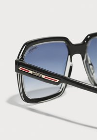 Ochelari de soare cu ramă neagră pătrată, cu lentile gradate de culoare albastră. Prezintă accente metalice de aur și roșu pe brațe. Suprafață texturată lângă balamale.