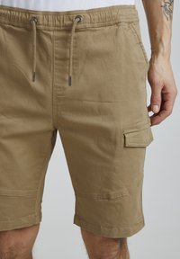Knee-lång khaki shorts gjorda av strukturerat tyg, med elastisk midja och dragsko samt en sidoficka.