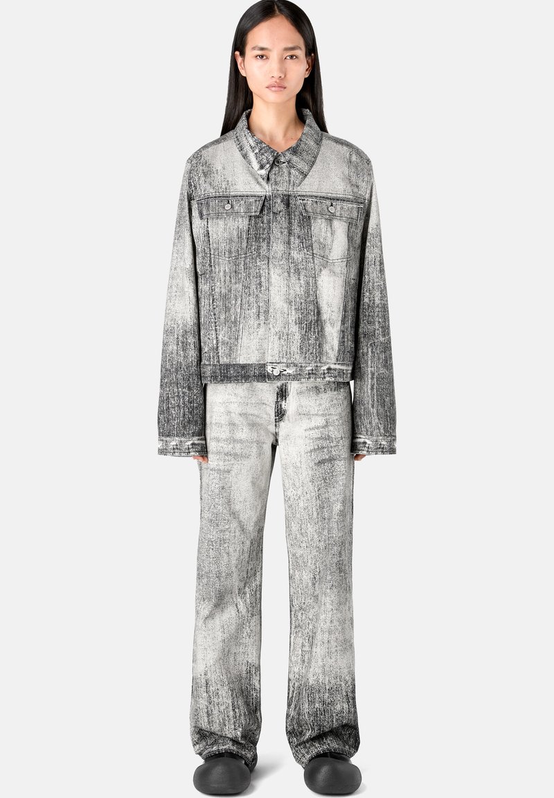 Schwarze und weiße Jeansjacke mit passender Hose, die über eine verblasste Textur, ein oversized Design und Knopfverschlüsse verfügt, kombiniert mit schwarzen Schuhen.
